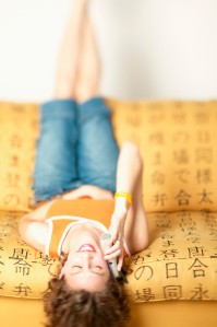 Young woman lying back on a couch talking on a mobile phone